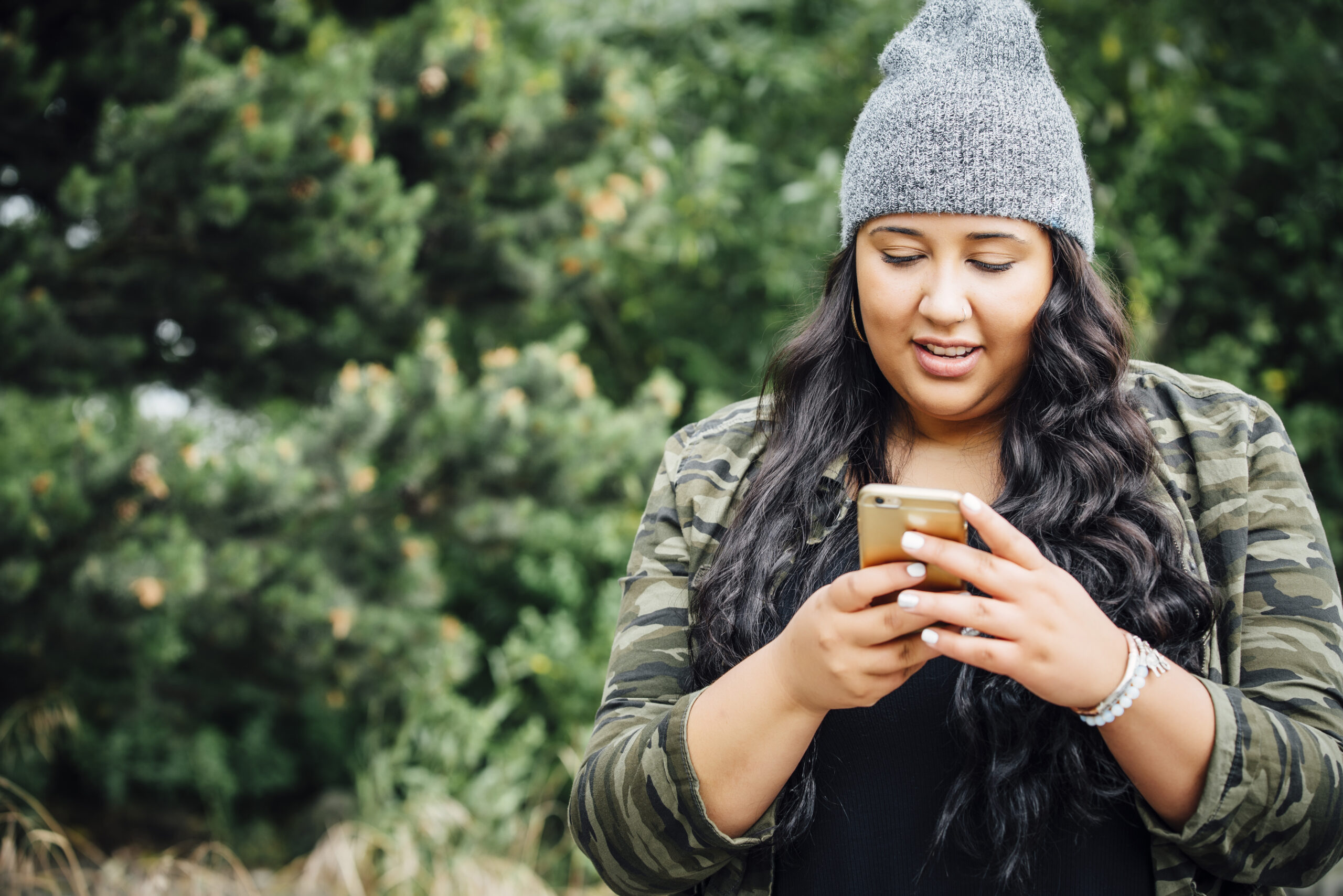 Mixed Race woman texting on cell phone in forest